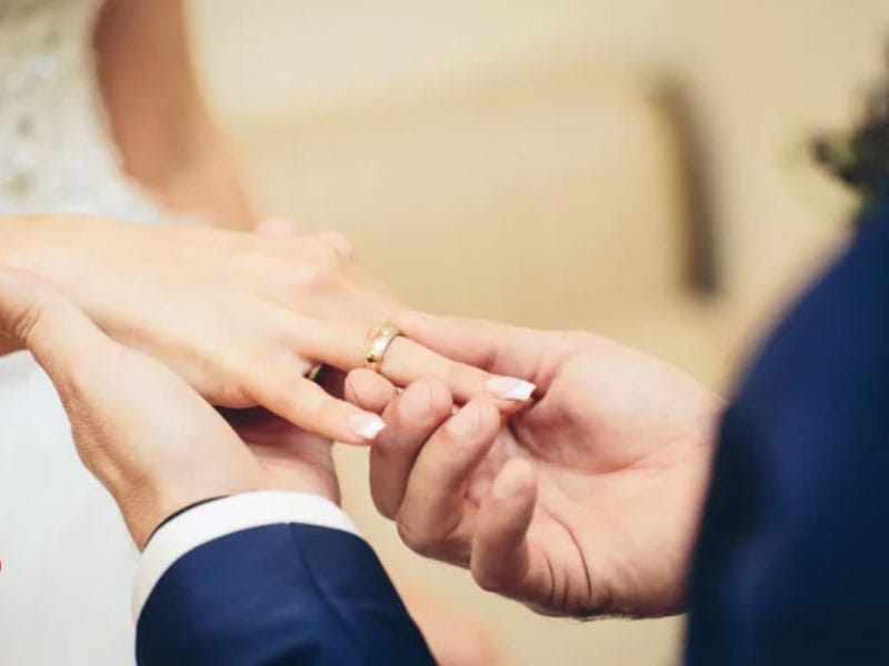 A bride and groom putting their wedding rings on each other's hands.