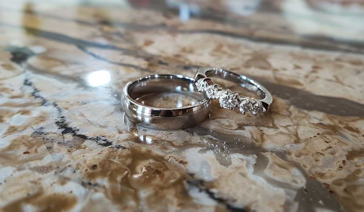 Two silver rings on a marbled surface; one is plain, and the other features a row of diamonds.