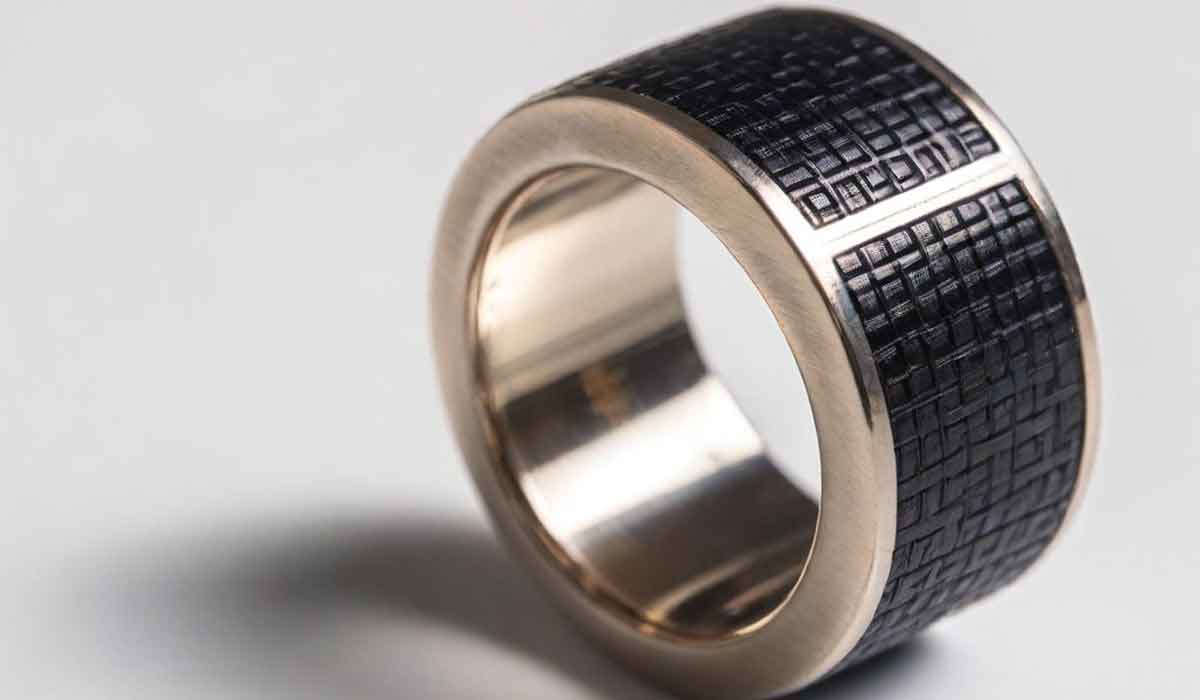 A wide metal ring with a black textured rectangular pattern on its outer surface, displayed on a light background.