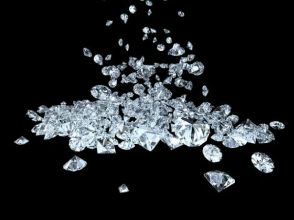 A collection of loose, polished diamonds scattered and falling against a black background.